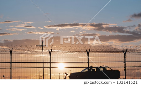 Airport security patrol driving along perimeter fence at sunset Airport security patrol driving along perimeter fence at sunset 132141521