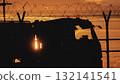 Airport service truck passing behind barbed wire fence at sunset 132141541