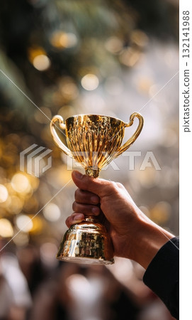 Shining Gold Trophy Held High in Celebration After Significant Achievement 132141988