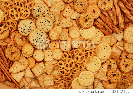 Colorful mix of salty crackers varieties: sticks and pretzels, triangular and round. Snacks food background 132142192