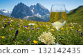 Glass of elderflower drink in an alpine meadow with wildflowers and a mountain view 132142435