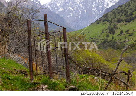 Rusty chain link fence with rotating wicket in mountains of Kyrgyzstan Rusty chain link fence with rotating wicket in mountains of Kyrgyzstan 132142567