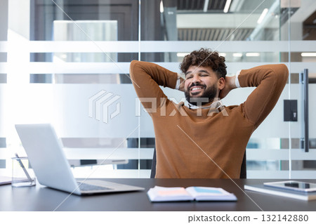 Happy smiling man with eyes closed relaxing in office, hands behind head, feeling satisfied and successful, enjoying a break after completing tasks at his laptop and desk Happy smiling man with eyes closed relaxing in office, hands behind head, feeling satisfied and successful, enjoying a break after completing tasks at his laptop and desk 132142880