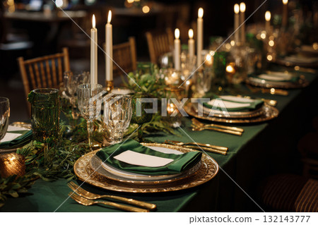 Wedding table setup with gold cutlery, crystal glasses, napkins and candlelight 132143777