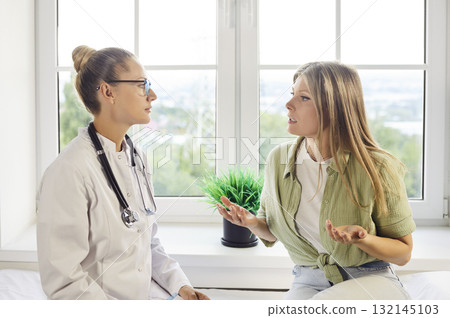 Doctor supports patient in consultation at bright clinic, empathetic conversation 132145103