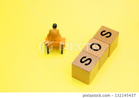 一塊寫著「SOS」的方塊和一個憂鬱的人 一塊寫著「SOS」的方塊和一個憂鬱的人 132145437