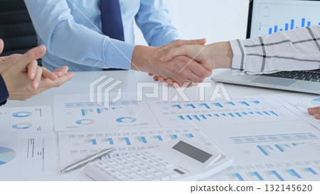 Business people shaking hands over financial documents and charts, confirming a successful agreement and partnership during a corporate meeting in the office Business people shaking hands over financial documents and charts, confirming a successful agreement and partnership during a corporate meeting in the office 132145620