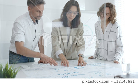 Professional colleagues reviewing financial reports, collaborating on strategic planning in contemporary workspace. Business people concept Professional colleagues reviewing financial reports, collaborating on strategic planning in contemporary workspace. Business people concept 132145681