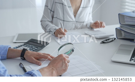 Groupe of accounting professionals analyzing financial documents, checking spreadsheet details with calculator and magnifying glass. Audit and taxes concept 132145853