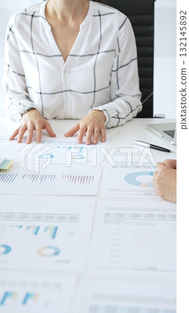 Team of business people reviewing financial charts and graphs during a business meeting, discussing strategy, data analysis, teamwork collaboration 132145892