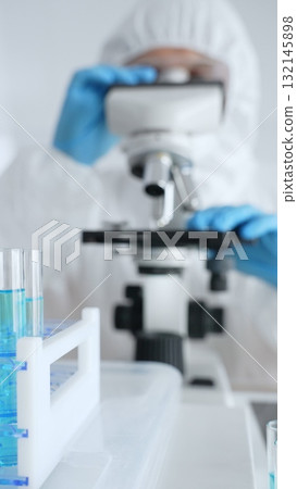 Scientific researcher wearing blue protective gloves fine tuning microscope lenses during medical laboratory investigation. Medicine, healthcare and science concept Scientific researcher wearing blue protective gloves fine tuning microscope lenses during medical laboratory investigation. Medicine, healthcare and science concept 132145898