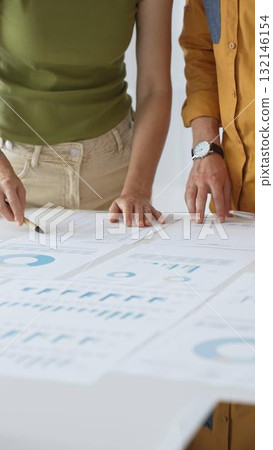 Business professionals analyzing financial reports, pointing at charts during collaborative meeting, discussing data with focused professional demeanor Business professionals analyzing financial reports, pointing at charts during collaborative meeting, discussing data with focused professional demeanor 132146154