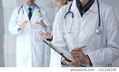 Medical professional writing on clipboard with stethoscope, a doctor and female assistant collaborating in a clinic, discussing patient data and healthcare information 132146198