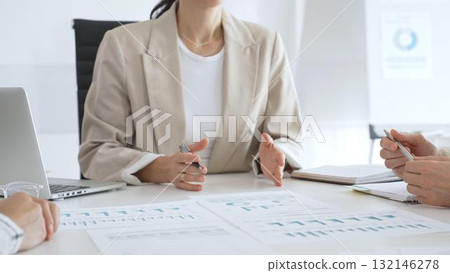 Business team analyzing financial data and discussing marketing strategy during a meeting in the office, businesswoman pointing at charts and explaining strategy to colleagues 132146278