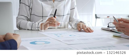 Business meeting with colleagues discussing financial charts, strategy planning, and analyzing data reports during a professional teamwork collaboration session Business meeting with colleagues discussing financial charts, strategy planning, and analyzing data reports during a professional teamwork collaboration session 132146326