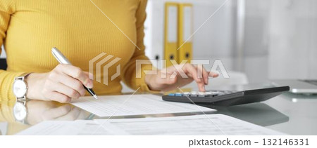 Woman calculating finance, taxes, and accounting paperwork at office desk, budgeting expenses, filing documents. Audit and taxes in business 132146331