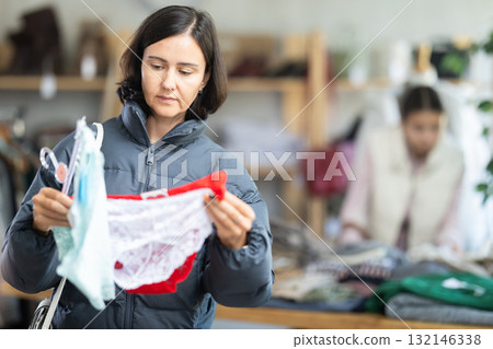 Woman looks at products in store and selects panties. Family shopping 132146338