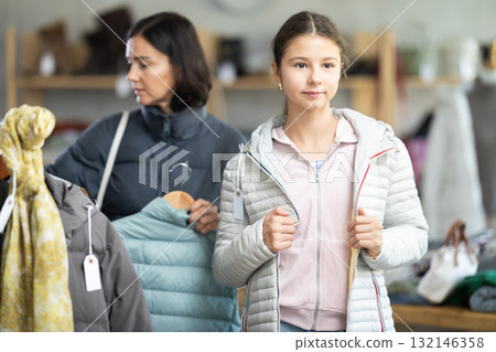 Teenage girl with her mother try on down jacket Teenage girl with her mother try on down jacket 132146358
