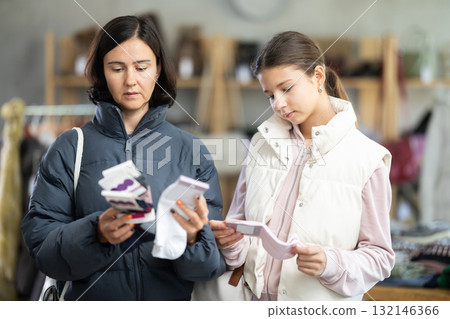 Mother and teen daughter looks at products in store and selects cotton socks. 132146366