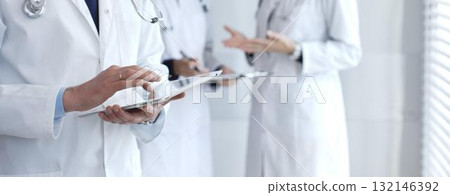 Healthcare professional using a digital tablet for patient data management as doctors collaborate on medical records in a modern, technology-driven clinic Healthcare professional using a digital tablet for patient data management as doctors collaborate on medical records in a modern, technology-driven clinic 132146392