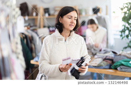 Woman looks at products in store and selects socks. Family shopping Woman looks at products in store and selects socks. Family shopping 132146498