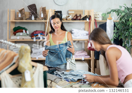 Mother and teenage daughter choosing jean shorts in clothing store 132146531