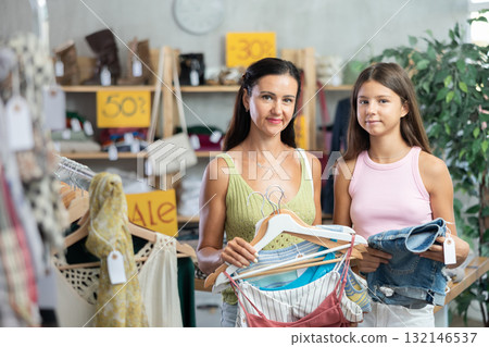 Near rack, daughter with mom buys something summer cloth, chooses items. 132146537
