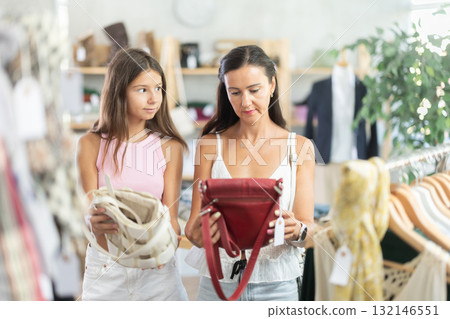 Mother and teenage daughter choosing handbag in clothing store 132146551