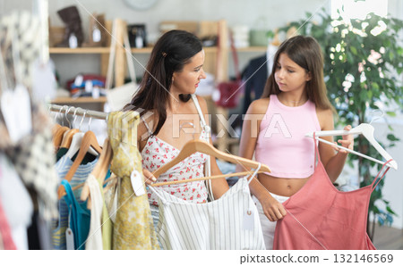 Near rack, mom with daughter buys summer dress, chooses items. Near rack, mom with daughter buys summer dress, chooses items. 132146569