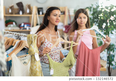 Mother and teenage daughter choosing something for summer in clothing store 132146572