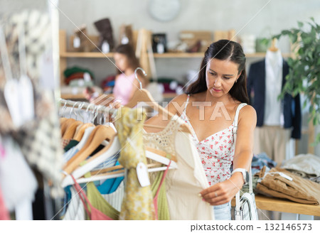 Middle-aged woman choosing something for summer in clothing store 132146573