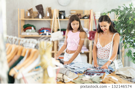 Mother and teenage daughter choosing jean pantaloons in clothing store Mother and teenage daughter choosing jean pantaloons in clothing store 132146574