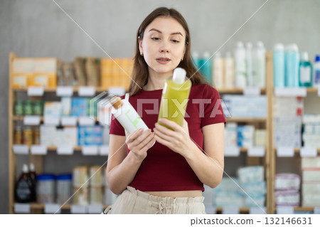 woman chooses a natural shampoo at the pharmacy 132146631