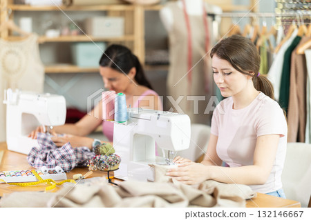 Two seamstresses working on sewing machines in sewing workshop Two seamstresses working on sewing machines in sewing workshop 132146667