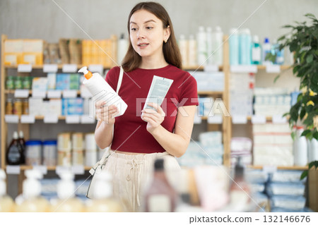 Young woman buyer select cream in drug store 132146676