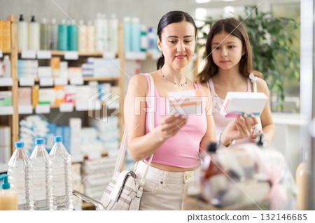 Woman buyer with teen daughter select pills in drug store Woman buyer with teen daughter select pills in drug store 132146685