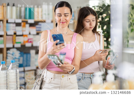 Woman with teen daughter in pharmacy scans QR code on toothbrush 132146686