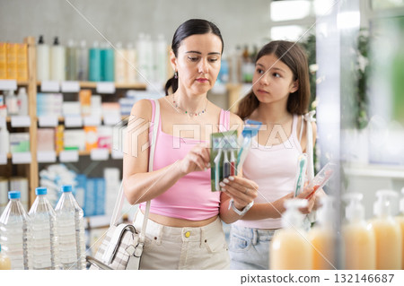 Friendly family of adult woman and young girl choosing best toothbrush at pharmacy 132146687