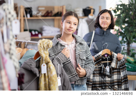 Adolescence girl try on plaid jacket during shopping with mother in clothes store 132146698
