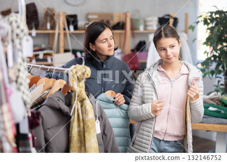 Teenage girl with her mother try on down jacket 132146752