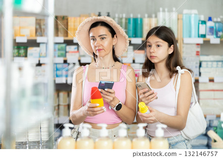 Interested mother and daughter customers preparing for summer season, holding and examines label and content of mosquito 132146757