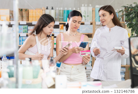 Family of mother and daughter clients choosing box of paracetamol antipyretic pills, scan QR code on label, looking at composition of medicine in drug store, young professional woman pharmacist 132146786