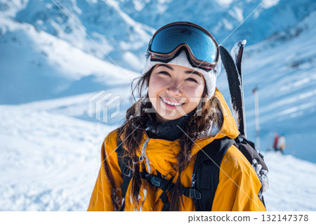 Happy young woman in a ski mask and orange jacket at a ski resort in winter. Beautiful skier in the mountains, the concept of winter sports, vacation 132147378