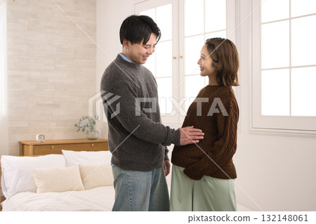 A young couple standing by the window, a pregnant woman A young couple standing by the window, a pregnant woman 132148061