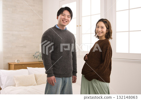 一對年輕夫婦站在窗邊,一名孕婦 一對年輕夫婦站在窗邊,一名孕婦 132148063