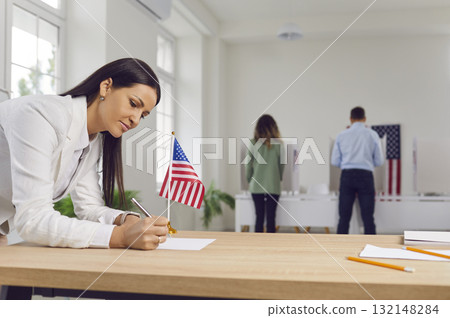 Woman fills out paper form on table at polling station during American elections 132148284