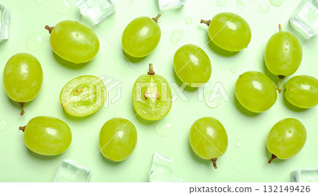 Flat lay of fresh green grapes, ice, and water drops on a pastel green background. Flat lay of fresh green grapes, ice, and water drops on a pastel green background. 132149426