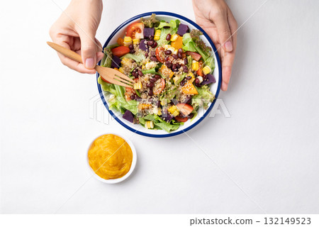 Healthy vegetable salad bowl eating with pumpkin dressing on white background Healthy vegetable salad bowl eating with pumpkin dressing on white background 132149523