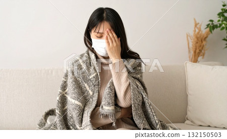 Woman wearing a mask and holding her head, measuring fever Woman wearing a mask and holding her head, measuring fever 132150503