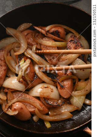Frying fish sausage and onion in a frying pan 132150511